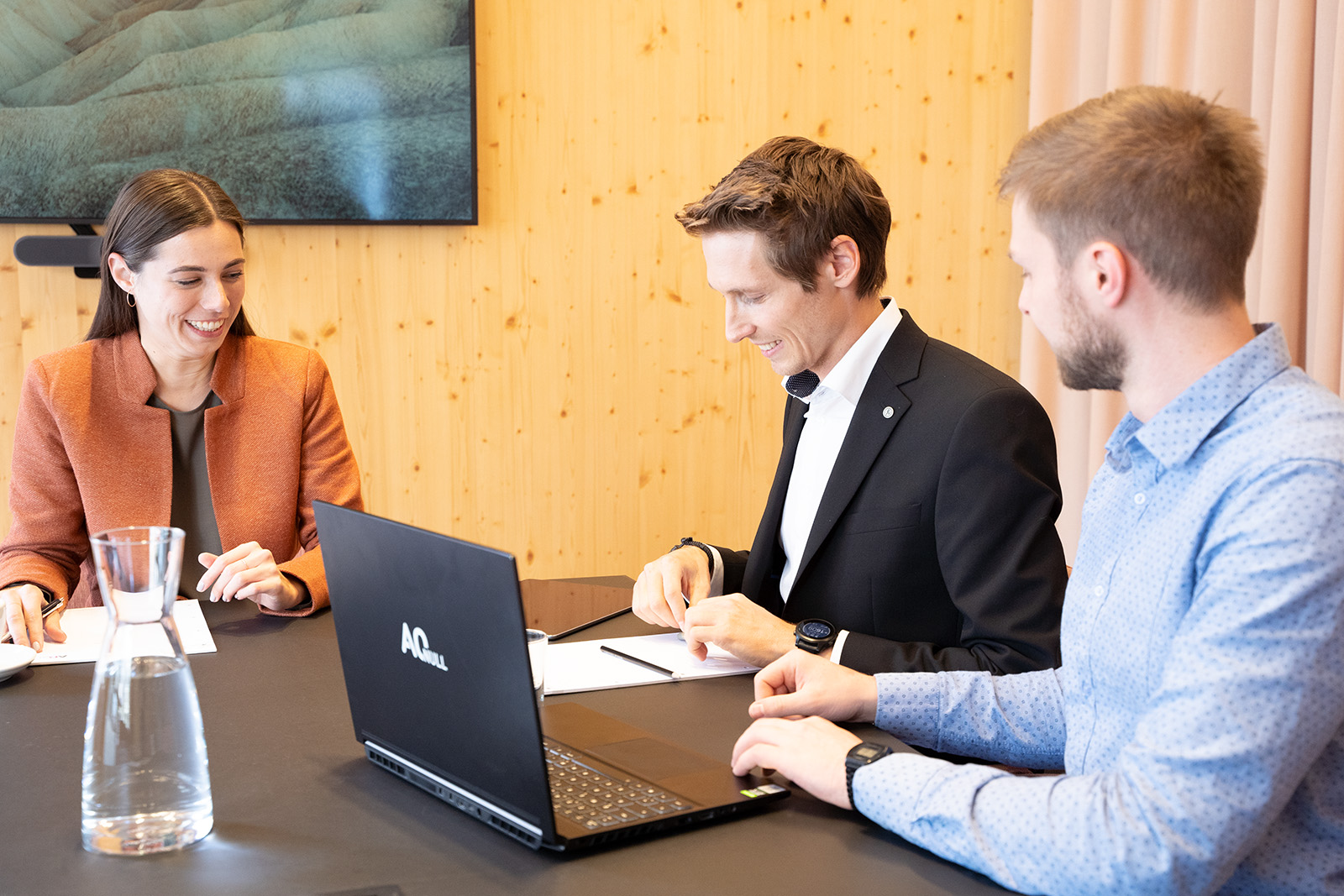 2 Consultants und eine Kundin sitzen gemeinsam am Tisch